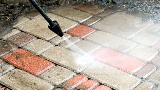 Close up of pressure washer wand cleaning block paving