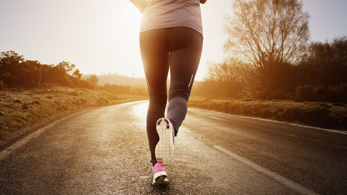 A woman road running at sunset