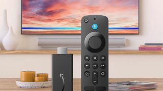 The Amazon Fire TV Stick HD and Alexa remote with a TV and soundbar in the background.