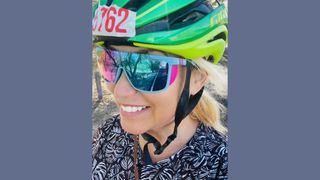 Tamara MC selfie smiling with reflection of the open road in her cycling glasses