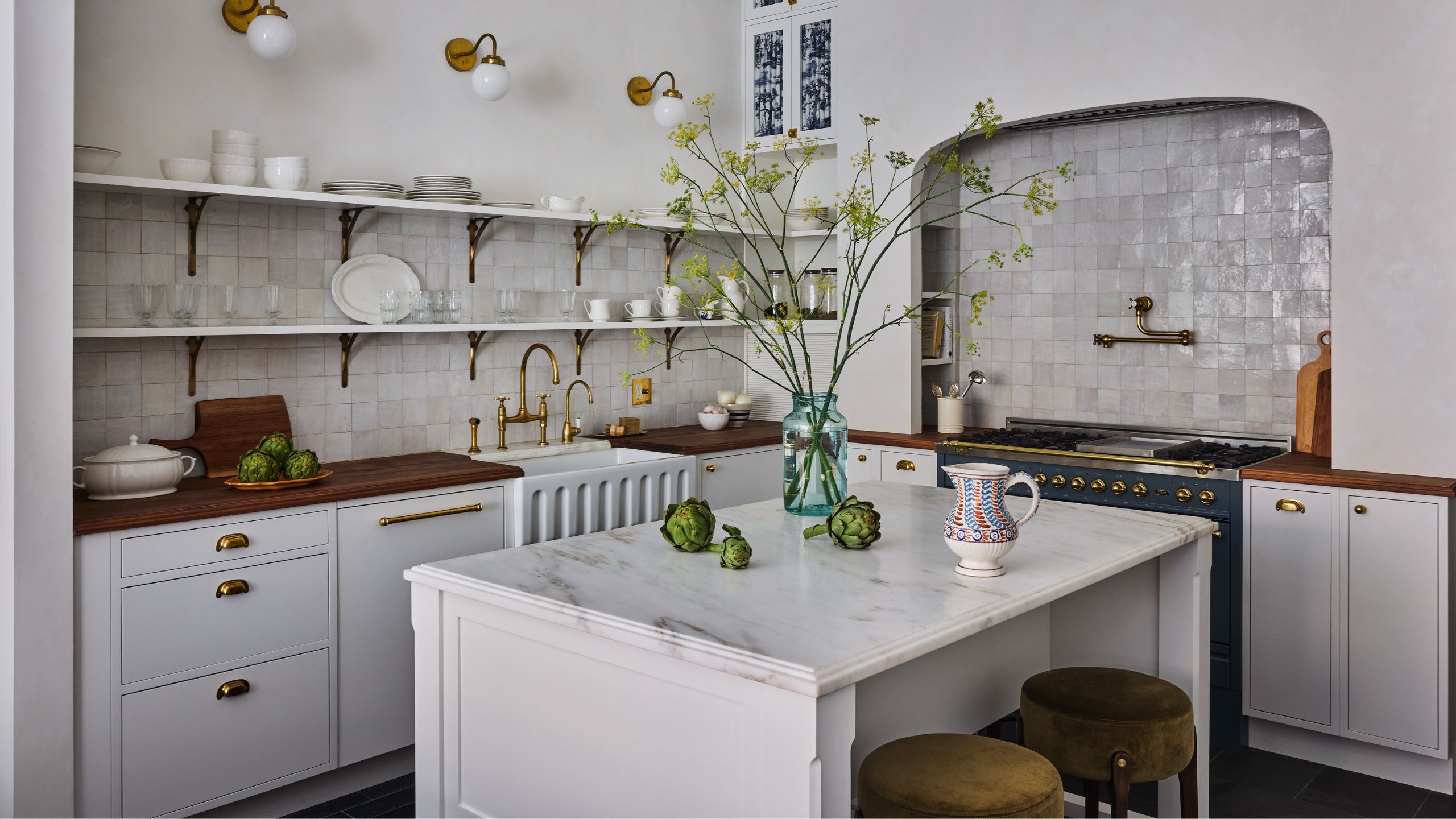 a warm rom-com inspired white kitchen with zellige tiles, a blue cooker, fluted sink and open shelving