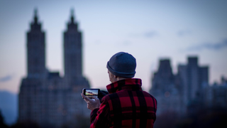 Man taking photo of city at a distance on his phone