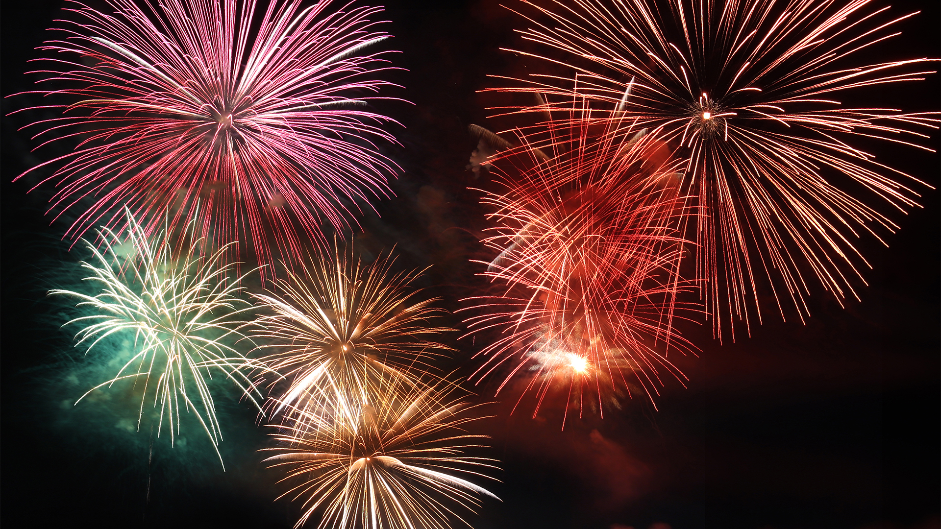 A series of brightly colored fireworks exploding against a dark sky