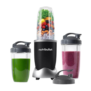 A Nutribullet Pro 900 Blender filled with ice and fruits and vegetables on a white background