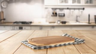 A wooden table in the kitchen with a wooden chopping board on top