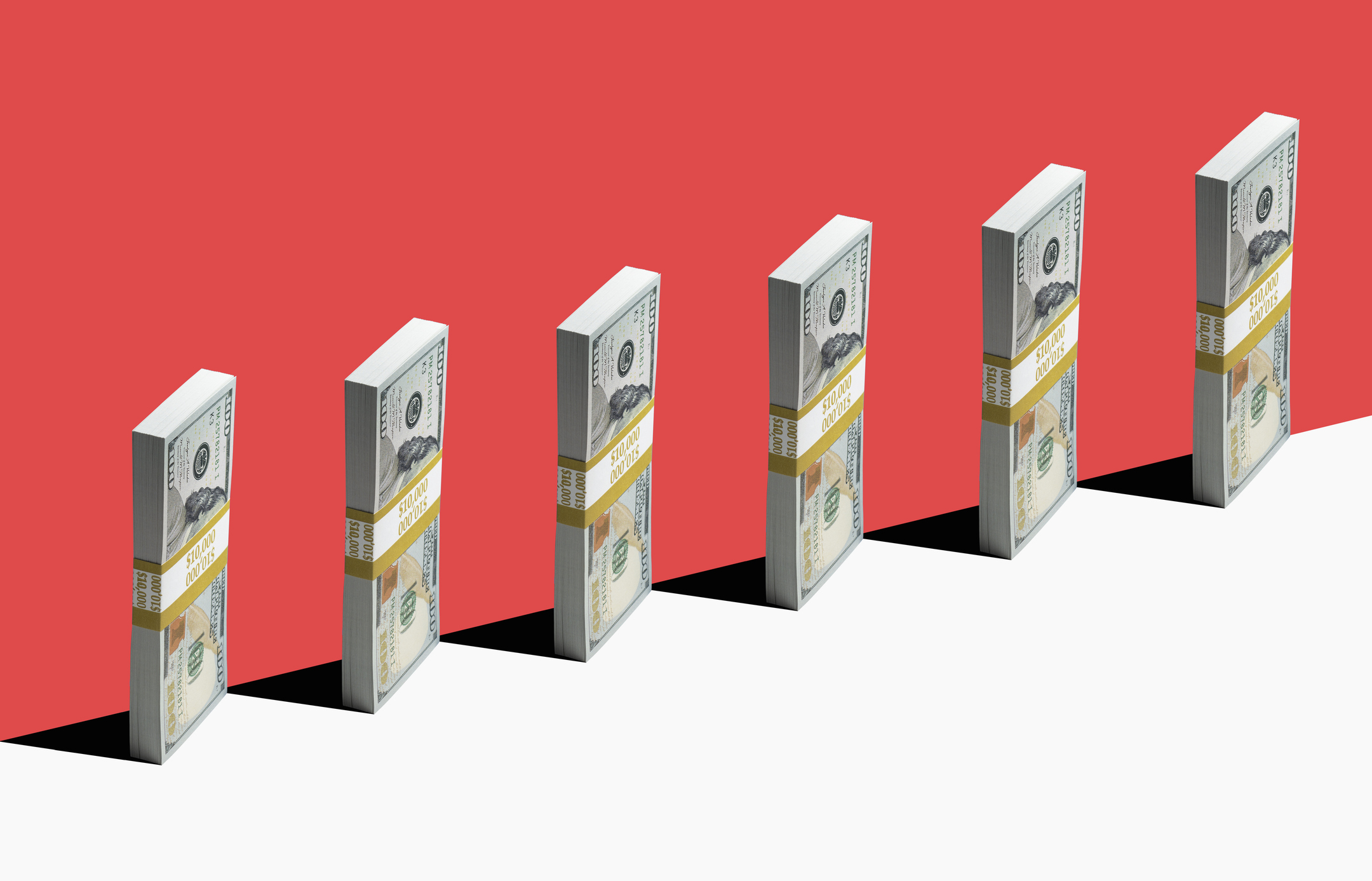 6 bundles of US $100 bills standing vertically on edge of white shelf, red background