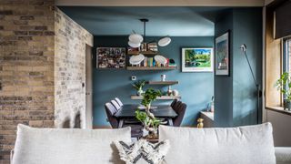 blue living area and dining room with sofa and exposed brick