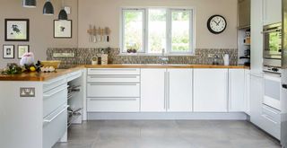 a neutral kitchen with beige walls and white cabinets kept clean and tidy to show how to organise a kitchen