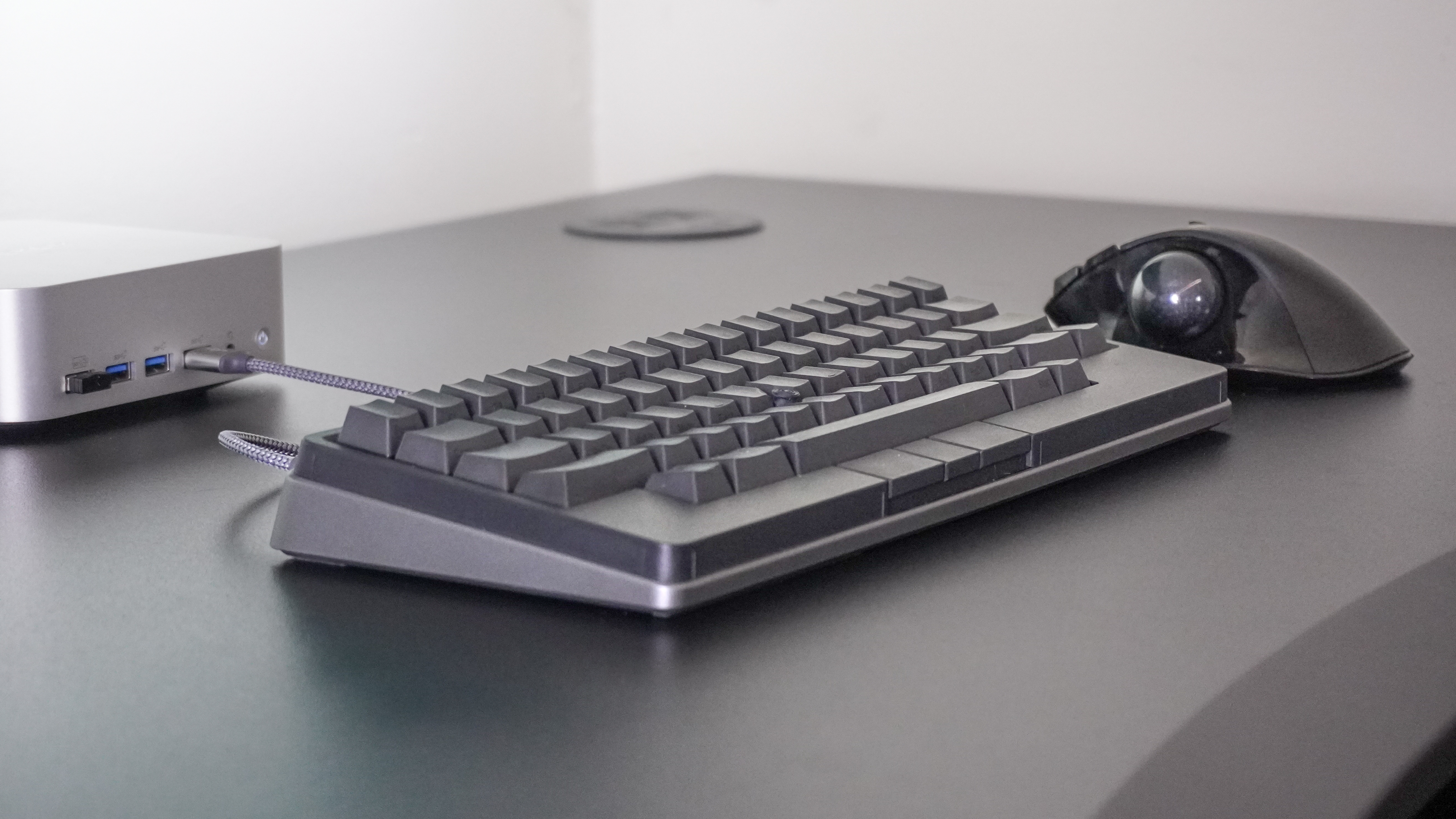 The HHKB Studio keyboard next to a trackball mouse and a mini PC on a desk