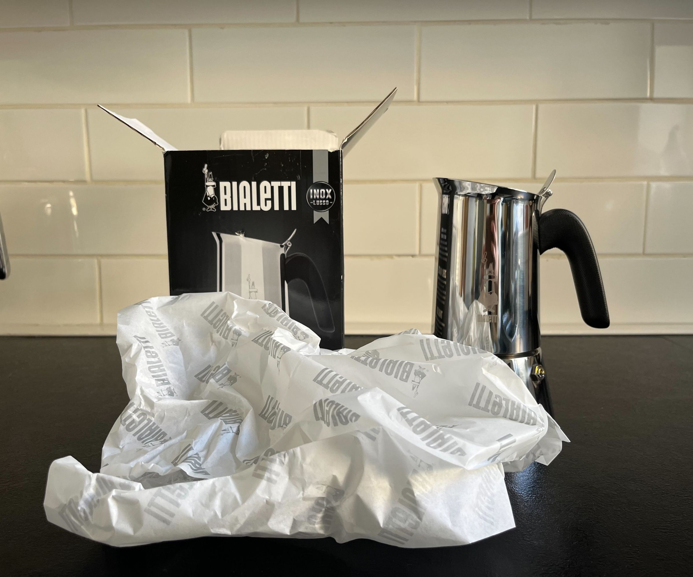 The stainless steel Bialetti Venus next to its box, with the recyclable paper packaging