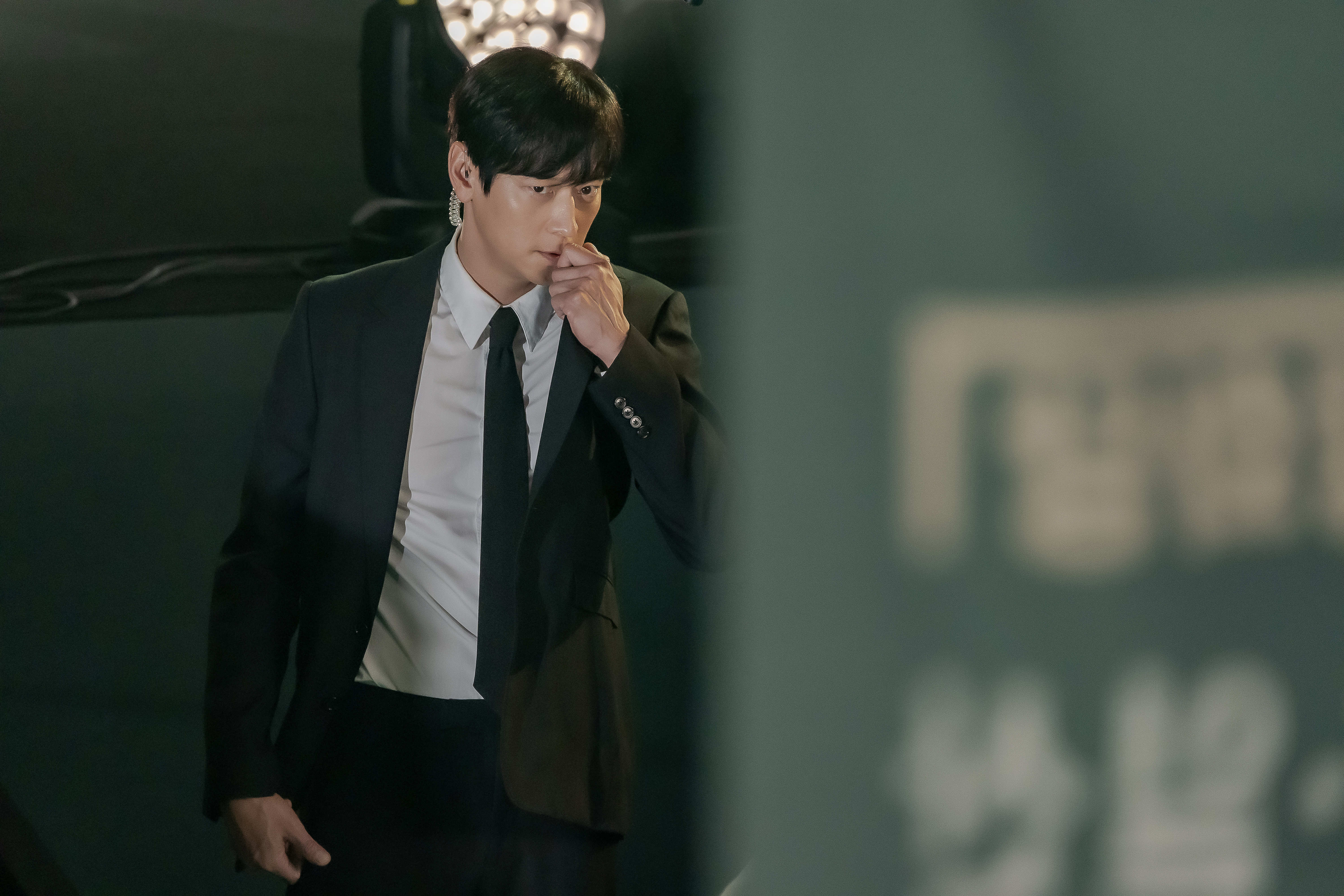 Gang Dong-won talks into an earpiece and wears a suit in &#039;Tempest.&#039;