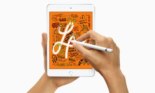 A person holding an iPad mini 5 and drawing on it with an Apple Pencil.