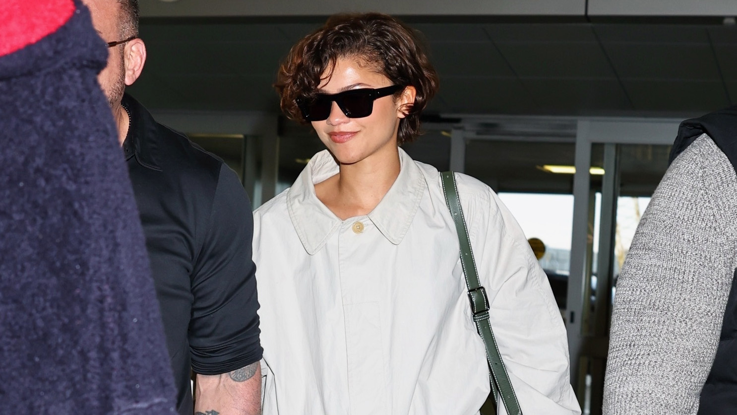 Zendaya wearing a The Row trench, skirt, and loafers at JFK airport