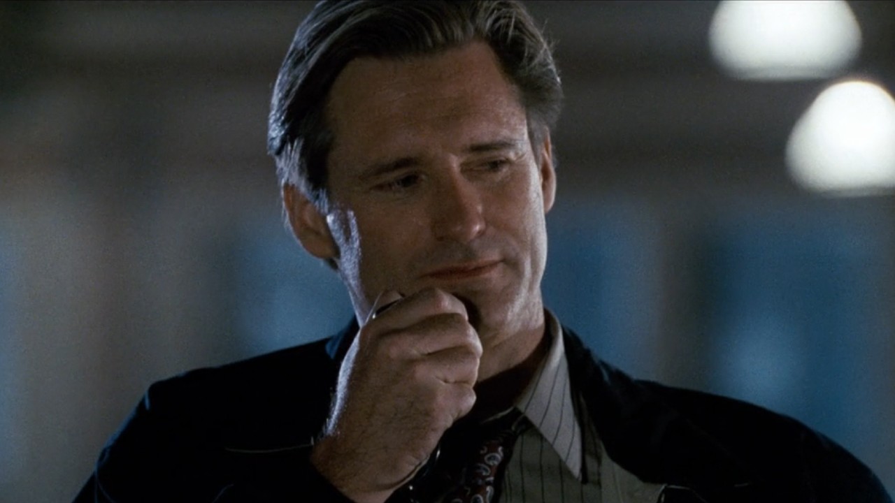 Bill Pullman in Independence Day holding a walkie up to his mouth with his left hand.