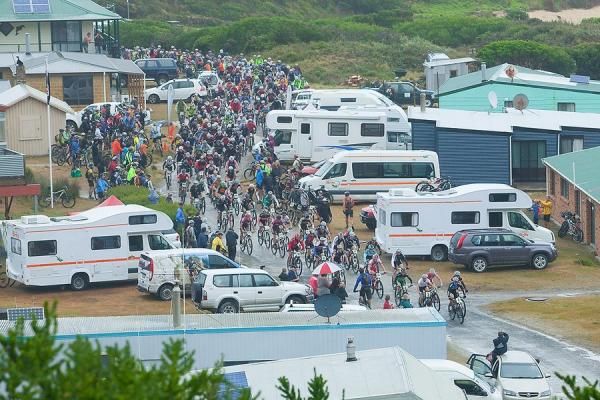 Around 500 riders stream through the usually sleepy main street of Trial Harbour at the start of stage 6.