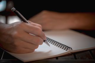 A photo of a person writing in a notebook.