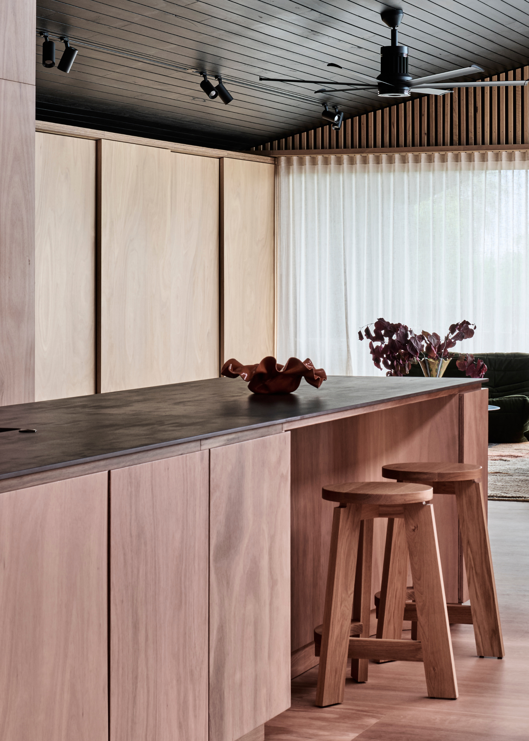 A laid back kitchen space with a wood island, a set of kitchen stools and a structured bowl