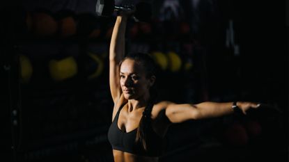 Woman doing a standing ab workout with a dumbbell
