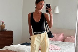 Tylynn Nguyen in a black tank top, trousers, and a black belt.