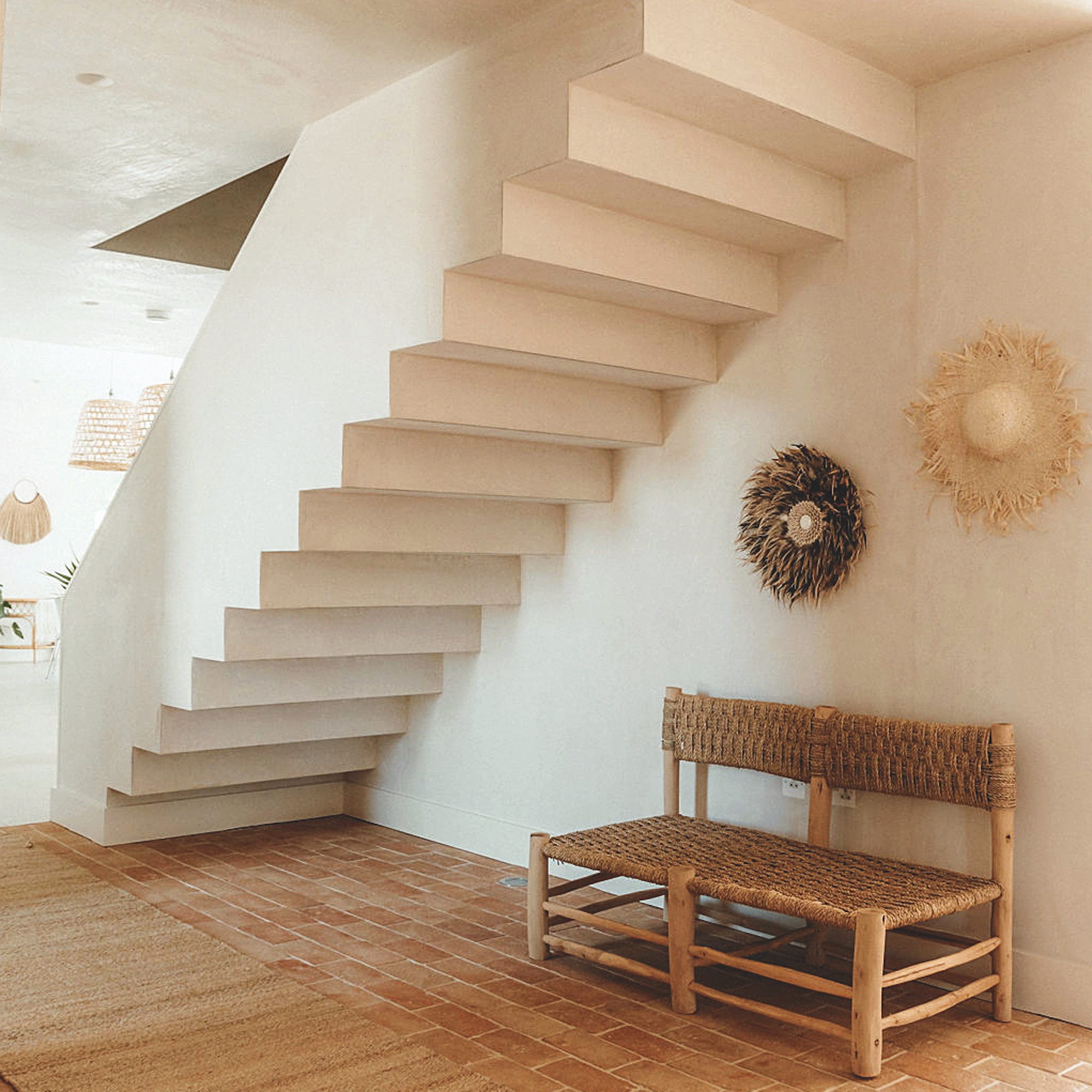 modern concrete staircase in hallway with brick floor and woven bench