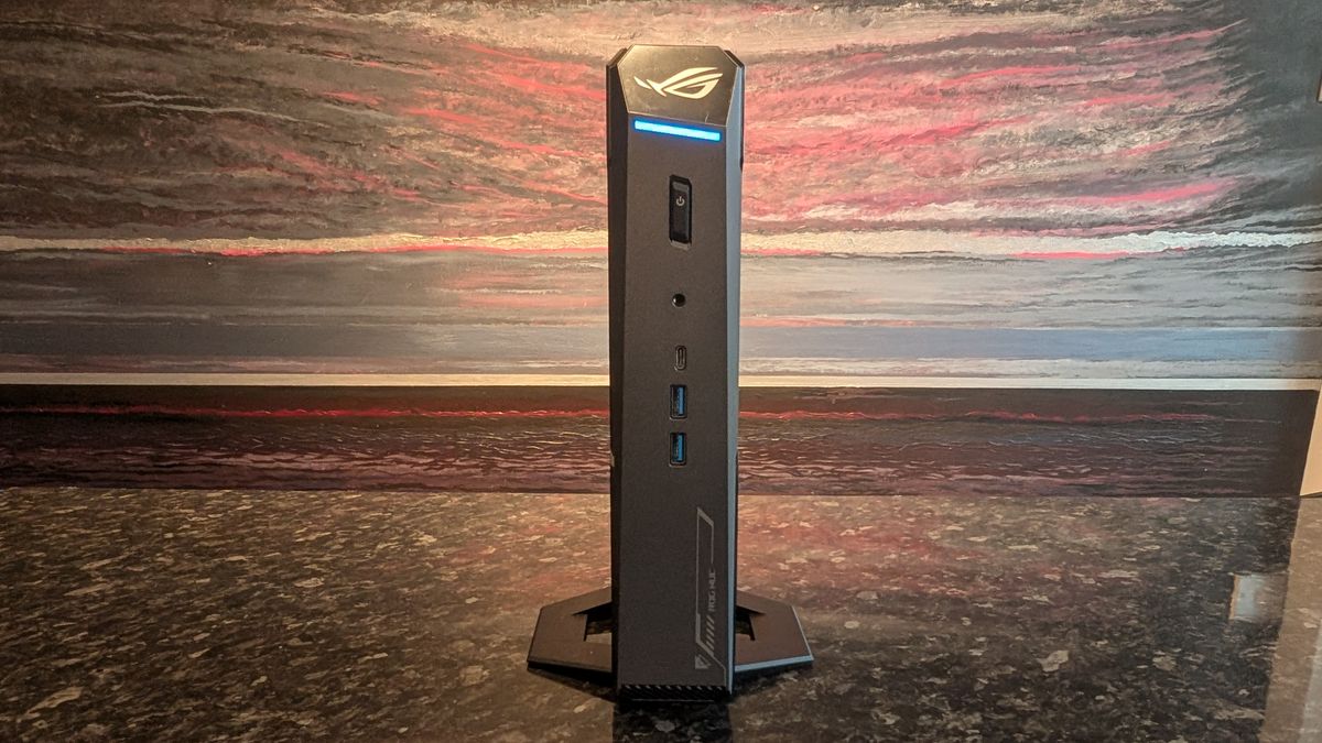 The Asus ROG NUC photographed on a dark marbled worksurface with a painted sunset in the background.