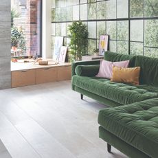 Green corner sofa in a living room with large windows