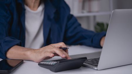 A man uses a calculator, only his torso and hand showing.