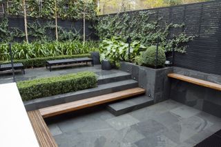 small garden with black paving, steps and fencing