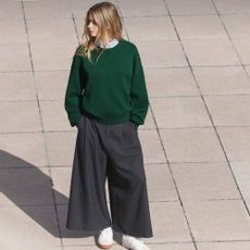 A photo from above of a woman modelling a green jumper and wide-leg grey slacks from Uniqlo