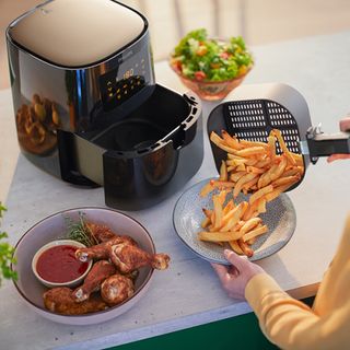 Philips Essential Air Fryer on kitchen counter next to roast chicken, chips and green salad