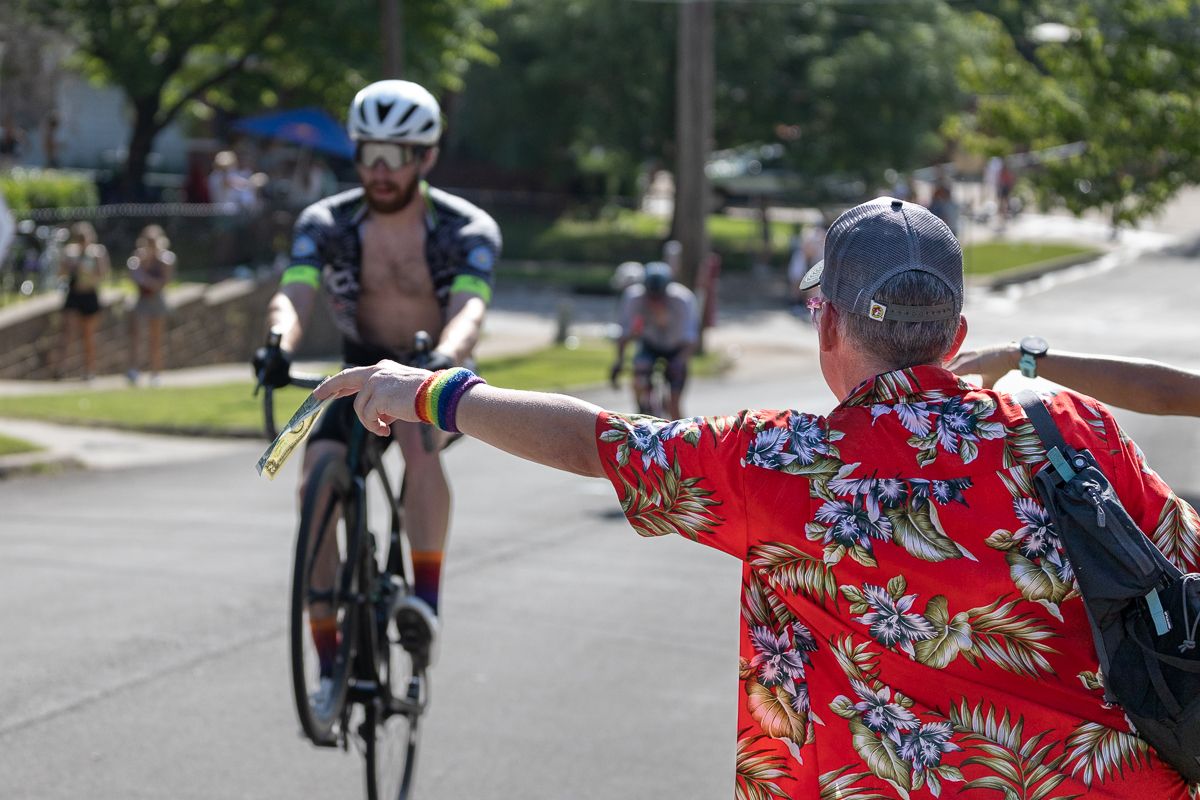 Andy Heuser (Team Audi McKinney-Encore Wire p/b Cadence Cyclery) entertains the fans on what is known locally as "Climax Corner", the highest point on the course while a spectator offers him a legitimate $2 bill.