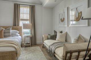 A neutral bedroom with a rattan bed, white walls, and a day bed along the side of the wall