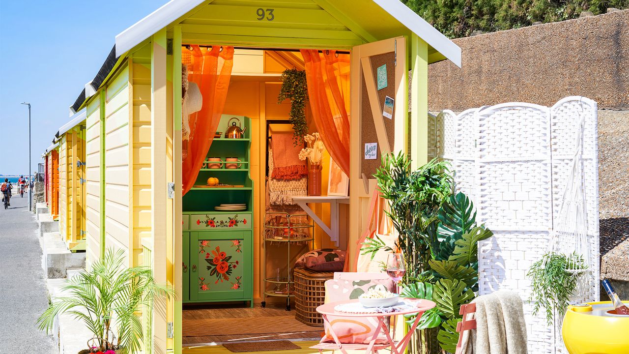 orange painted beach hut with bistro set outside