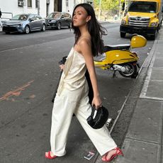 woman in silk top, jeans, and red sandals