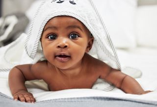 Cute baby having tummy time while wearing hooded towel