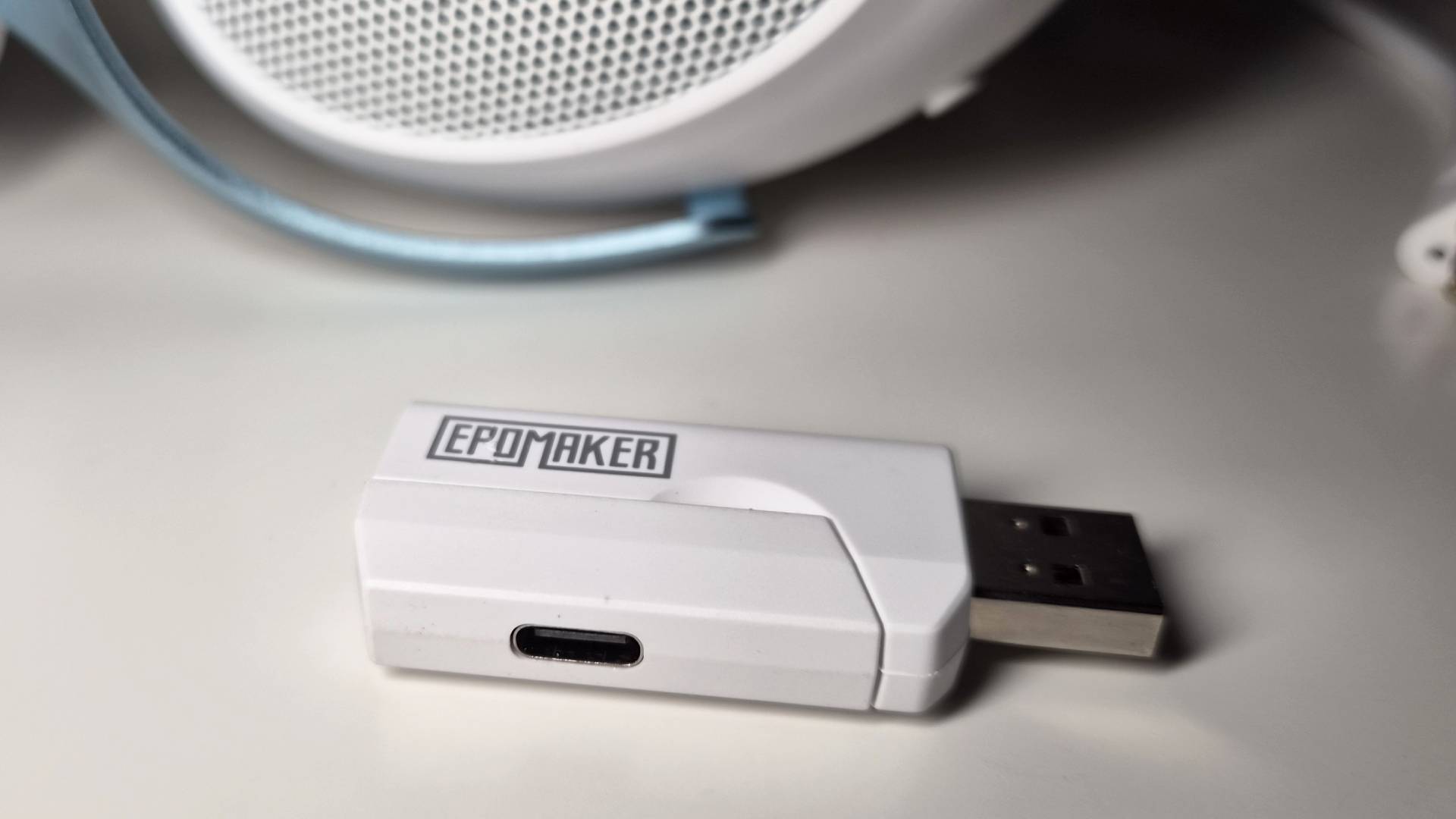 Photo of the Epomaker GX1 headset dongle sitting on a white desk.