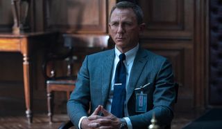 No Time To Die Daniel Craig sitting in M's office, in a grey suit