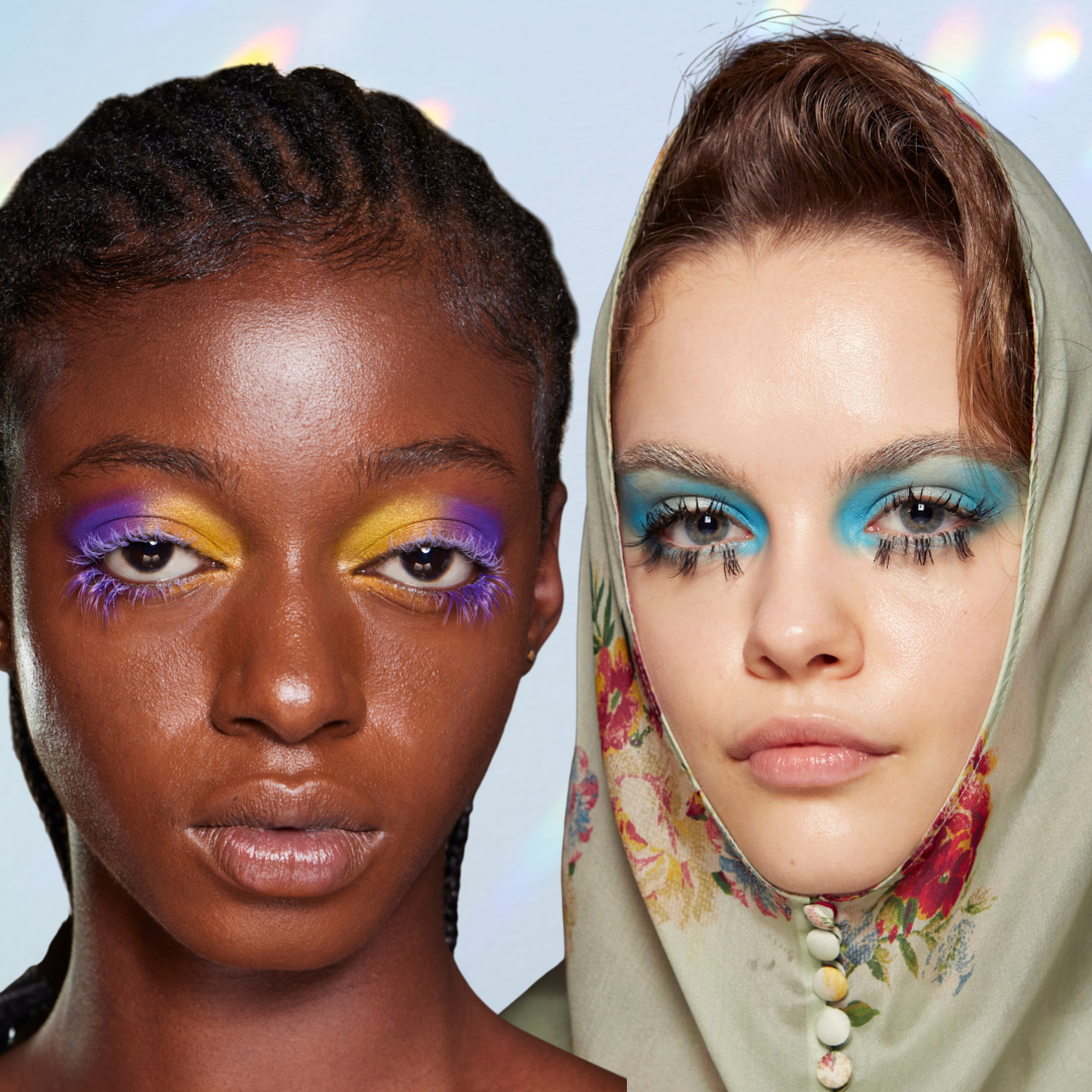 Two models with dramatic eye lashes in front of a blue background