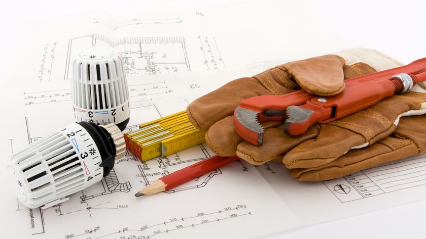 architectural plans with radiator valves, pencil, folding ruler, gloves and wrench on top 