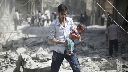 A Syrian man carries a wounded baby following a nair strike by Syrian government forces in the rebel-held area of Douma