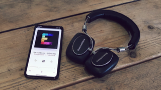Bowers & Wilkins headphones next to iPhone playing podcast