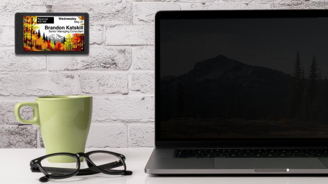 Visix e-paper solutions on a wall in front of a coffee and laptop.
