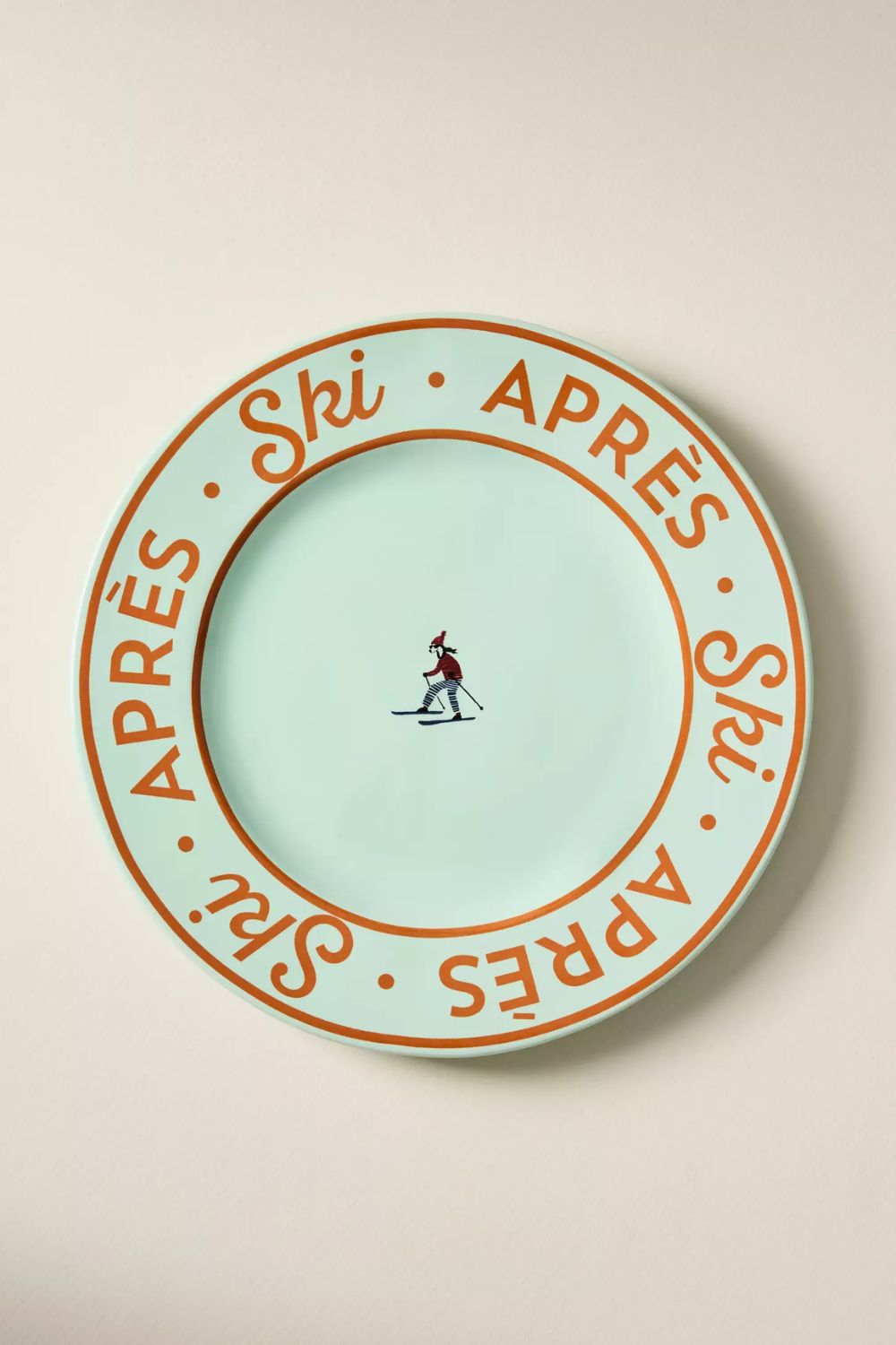 Mint green dessert plate with orange &#039;apres ski&#039; text and a central skiing motif