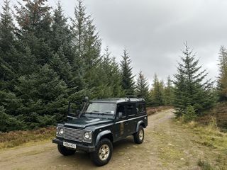 A dark Range Rover from Highland Safaris is parked on a road in a mountain in Perthshire