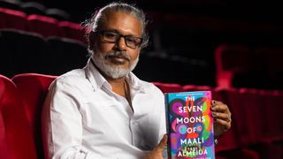 Author Shehan Karunatilaka holding book The Seven Moons of Maali Almeida