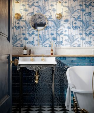 blue and white wallpaper in bathroom with blue metro tiles and vintage style sink and washstand