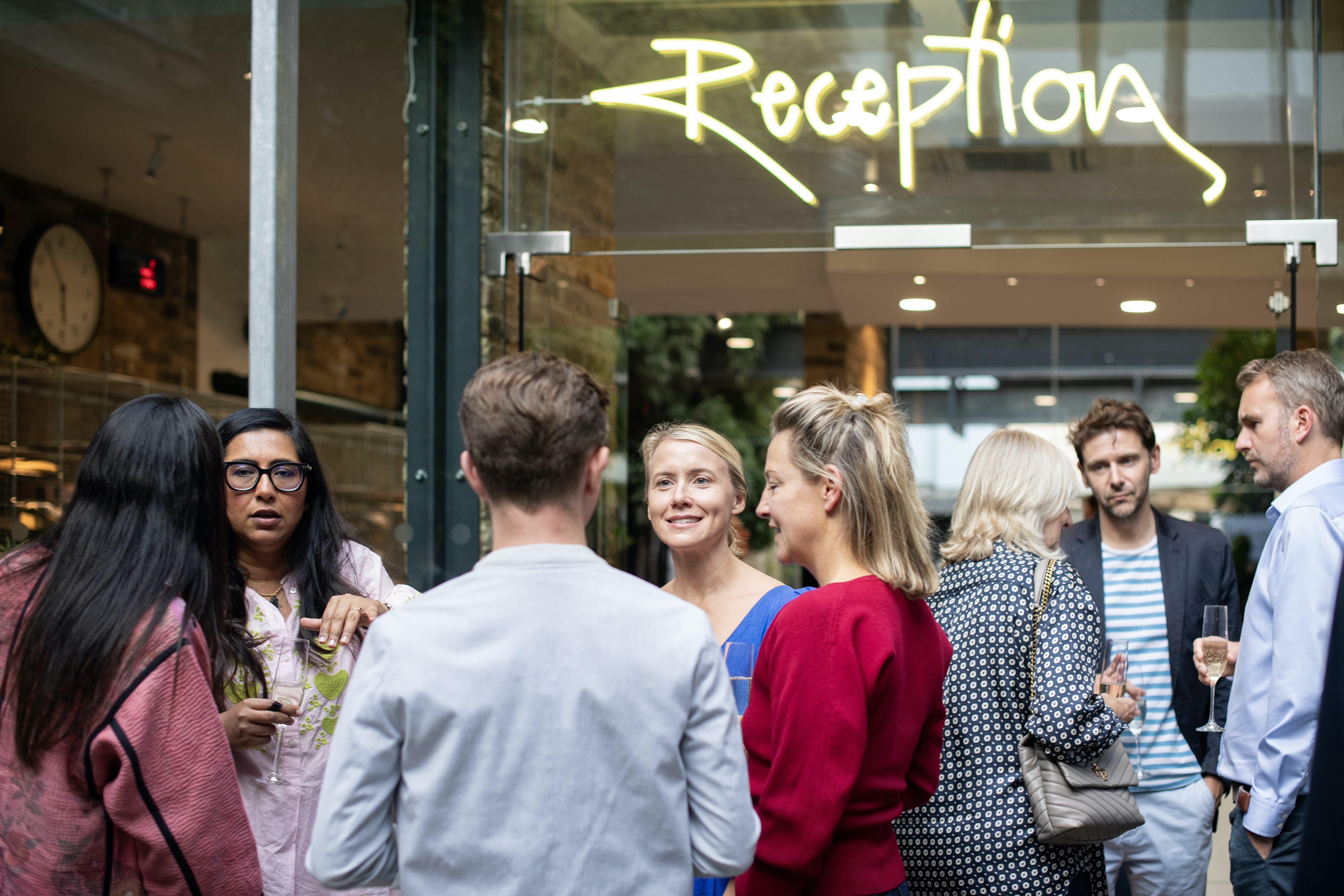 people talking outside of a building with a reception sign