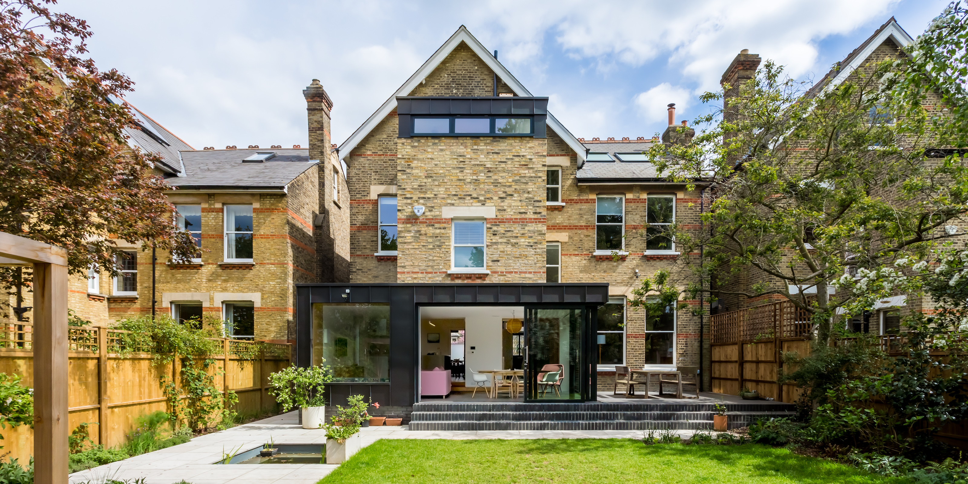 Detached house viewed from rear garden with large highly glazed extension