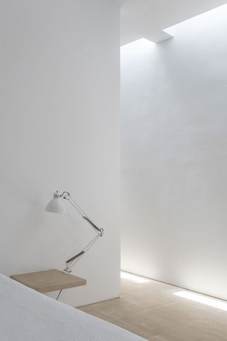 minimalist bedroom with lamp on a shelf next to the bed