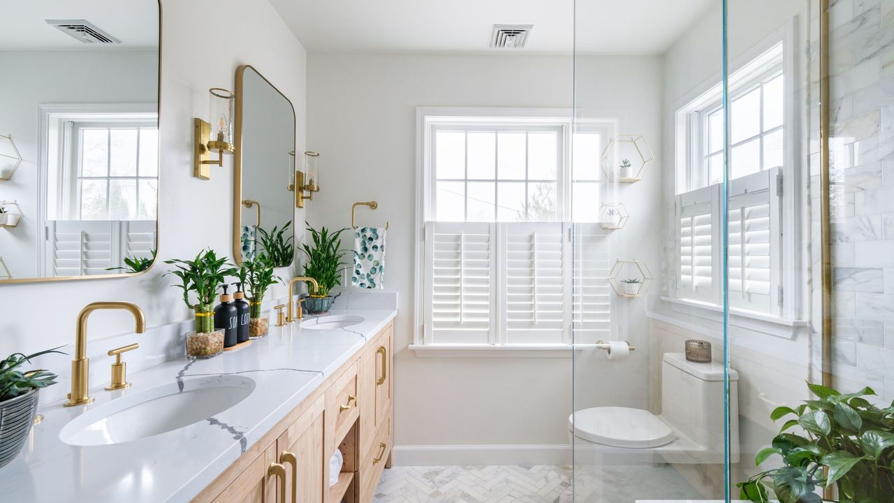 Learning how to maximize space in a small bathroom like this one is useful. It&#039;s a white bathroom with mirrors, a dual sink, shower, toilet, and window